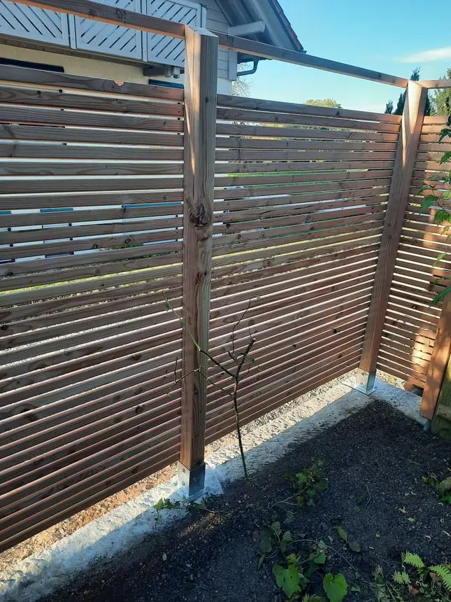 Sichtschutzwand aus waagerechten Holzlatten zwischen Holzpfosten auf verzinkten Pfostenträgern